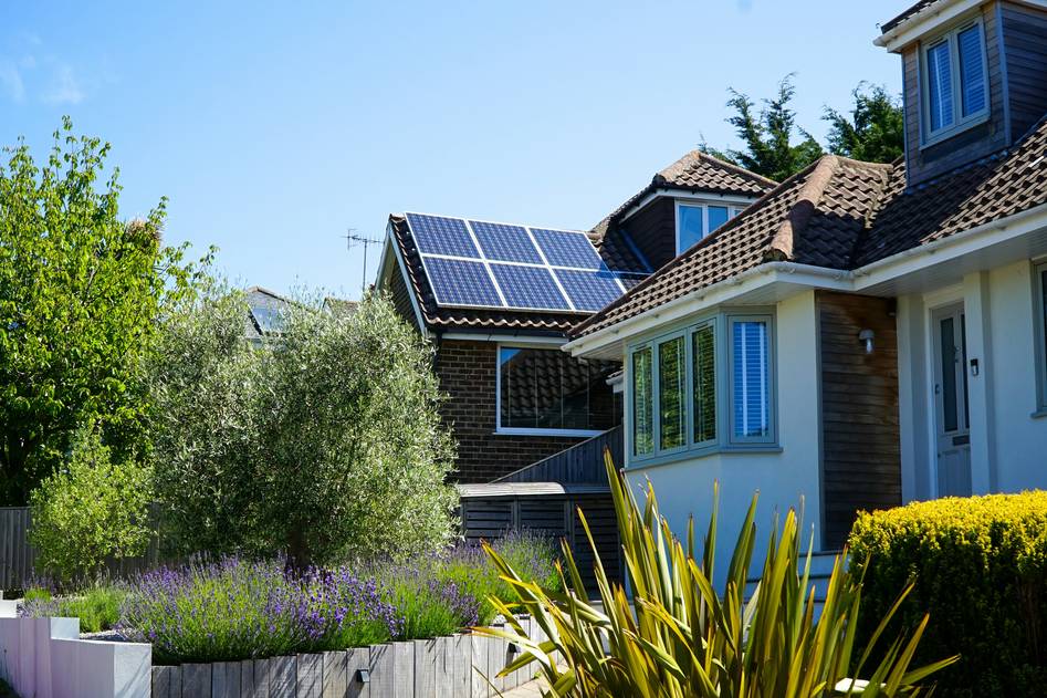 Modern string inverter mounted on a residential solar panel system with clear blue sky background